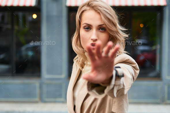 Beautiful female model in summer city in Europe. Trendy woman posing on the  street background. Fashion model girl feeling sad angry and upset outdoor.  Urban vogue girl. Stock Photo