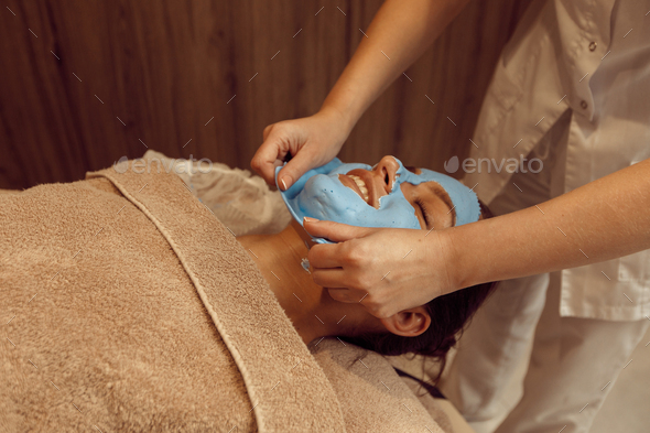 Masseur removes the cream mask from face of woman - Stock Photo - Images