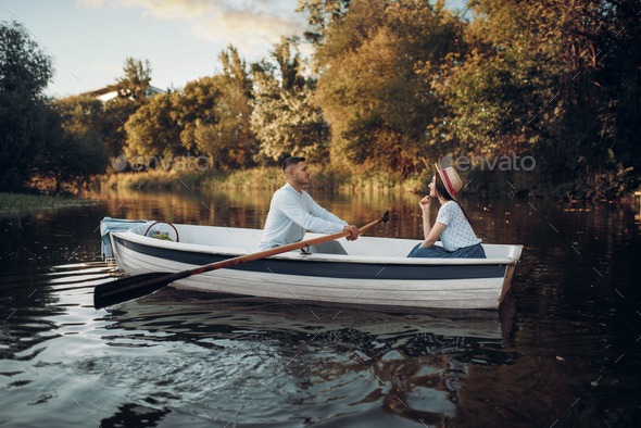 Love couple boating on lake, water reflection