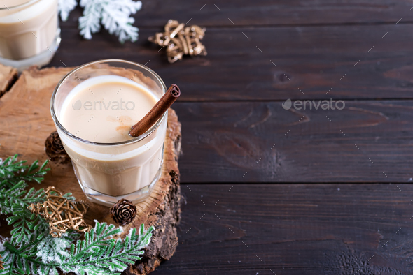 Eggnog Christmas milk cocktail, served in two glasses on a wood cutting board with fir branch and - Stock Photo - Images