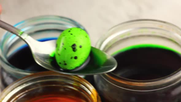 a Child Holds in a Metal Spoon a Green Dyed Easter Quail in a Dotted Egg on Glass Jars with alt