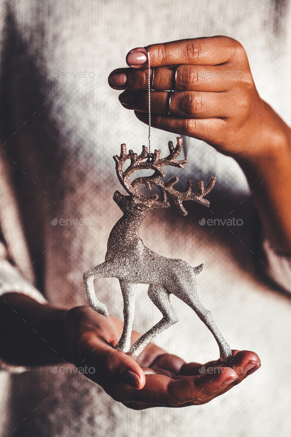Woman in warm sweater holding toy deer glass decorative ball in hands, copy space. Christmas - Stock Photo - Images