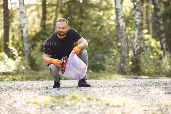 Man collects garbage in garbage bags in park