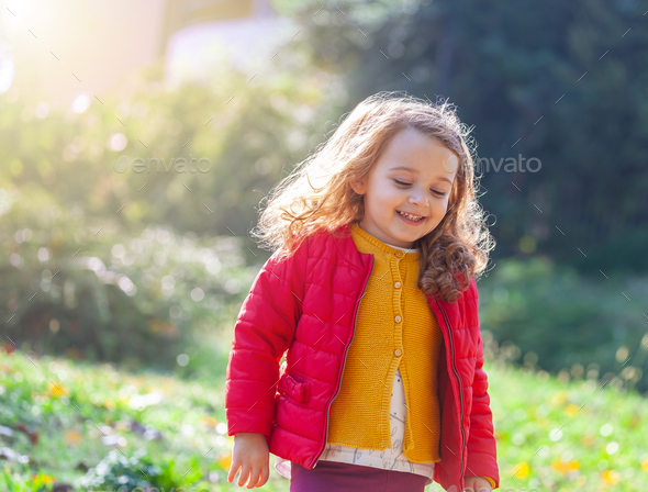 Adorable little girl walking in park on a fall day. - Stock Photo - Images