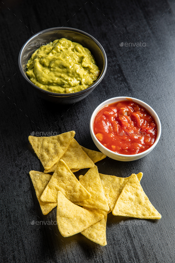 Corn nacho chips with avocado and tomato dip. Stock Photo by jirkaejc