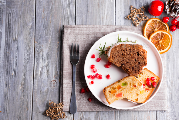 Christmas sliced chocolate cake and fruit cake with white icing and pomegranate kernels on plate - Stock Photo - Images