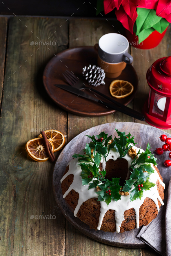 Christmas dark chocolate cake decorated with white icing and holly berry branches with red lantern - Stock Photo - Images