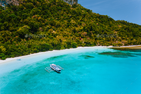 Aerial view of boat moored at secluded tropical beach with white sand, turquoise colored ocean - Stock Photo - Images