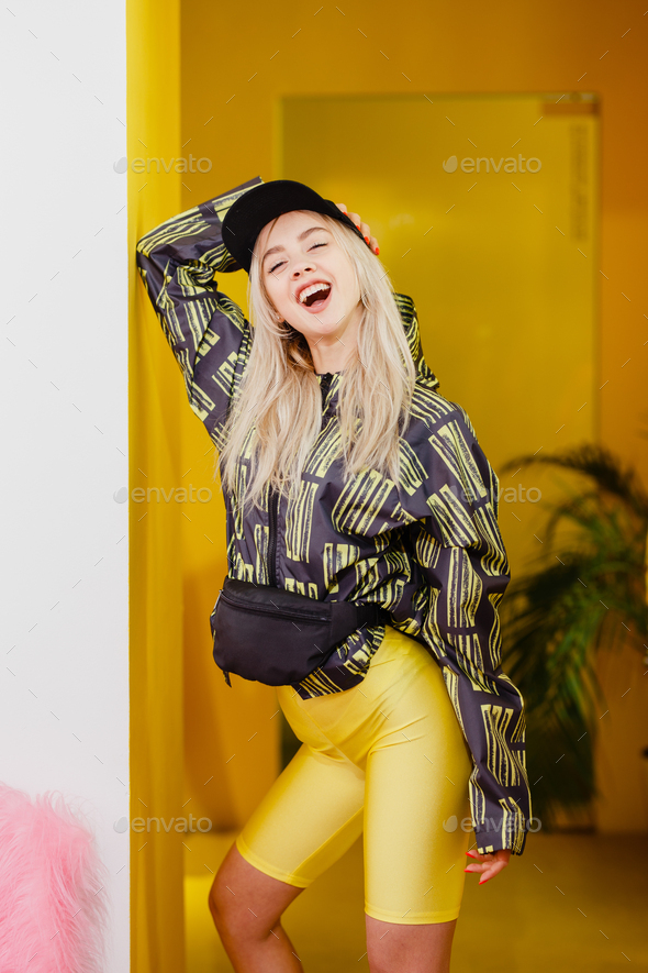 Young fashion girl blogger with black cap on the head dressed in a stylish black and yellow jacket - Stock Photo - Images
