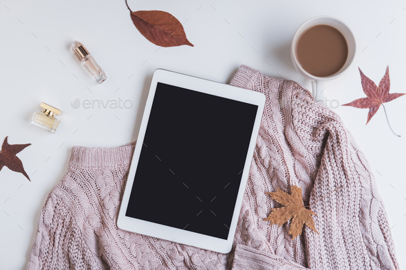 Empty screen tablet with cup of coffee and dried autumn leaves and sweater, Top view