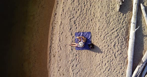 Woman with her pet dog sitting near the river coast on a sunny day 4K 4k alt