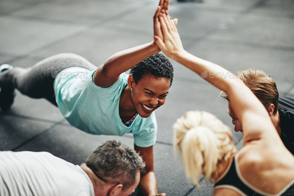 Laughing women high fiving while planking in a gym class - Stock Photo - Images