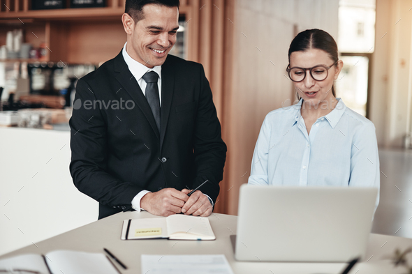 Two smiling businesspeople working on a laptop in an office