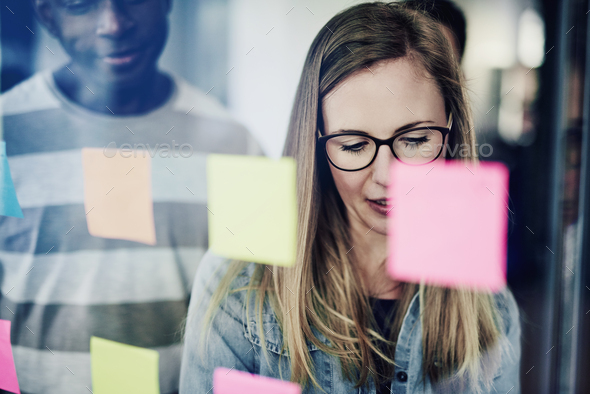 Businesswoman brainstorming with coworkers on an office window - Stock Photo - Images
