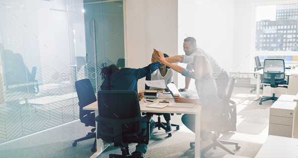 Smiling office workers high fiving together during a meeting - Stock Photo - Images