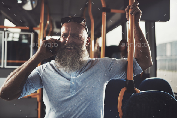 Smiling mature man standing a bus talking on his cellphone
