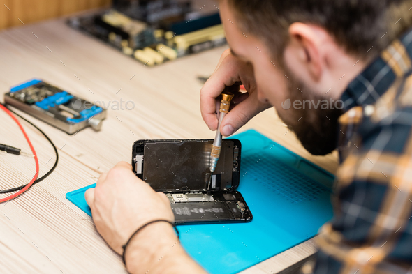 Professional gadget repair service master fixing tiny details with screwdriver