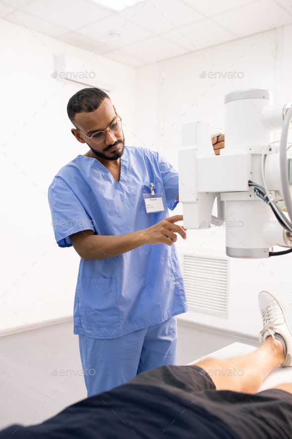 Young mixed-race man using new medical equipment to serve one of patients
