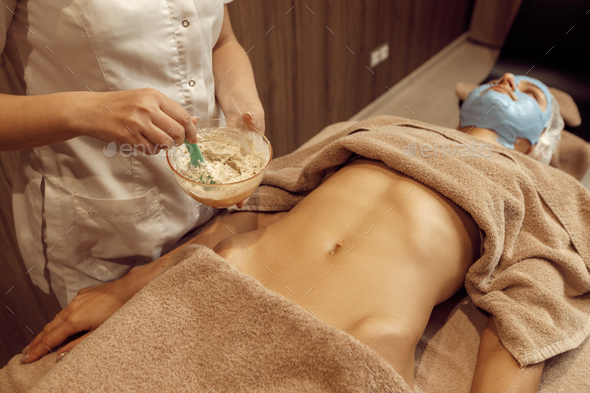 Female masseur applies cream on stomach of woman - Stock Photo - Images