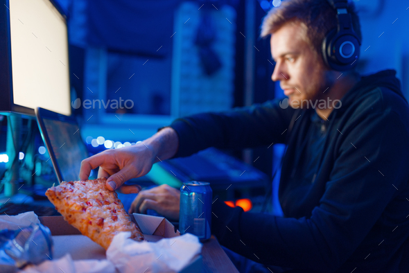 Male gamer eating pizza, night tournament - Stock Photo - Images