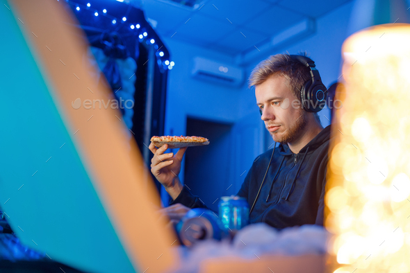 Male gamer eating pizza, night tournament - Stock Photo - Images