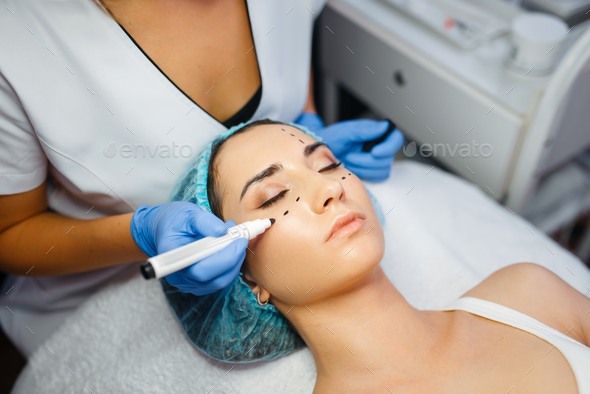 Cosmetician with marker puts dotted lines on face - Stock Photo - Images