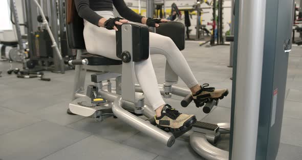 Woman Performs the Exercise of Raising the Legs in the Simulator alt