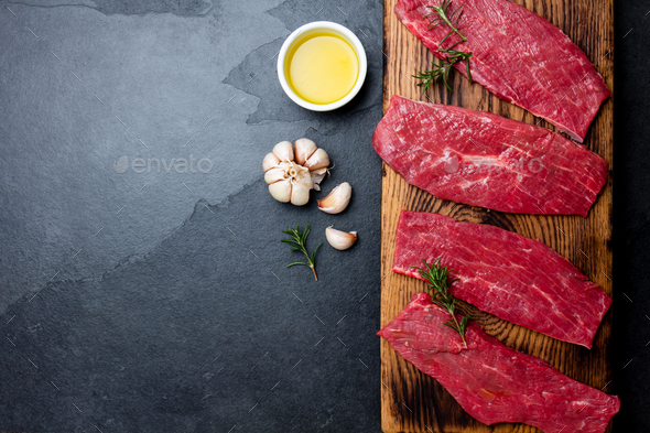 Beef tenderloin on wooden board, spices, herbs, oil on slate gray background. - Stock Photo - Images
