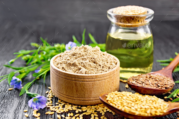 Flour linen in bowl with oil and flowers on dark wooden board - Stock Photo - Images