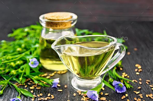 Oil flaxseed in gravy boat and jar on board - Stock Photo - Images