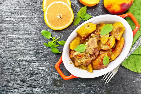 Turkey with peaches in pan on dark board top - Stock Photo - Images