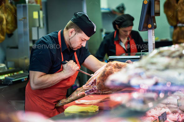 Butchers boning a ham in a modern butcher shop