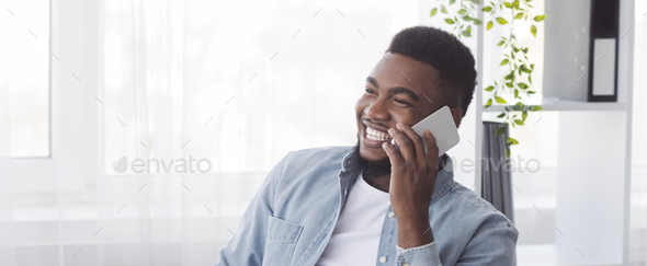Cheerful african american employee having pleasant phone call at work