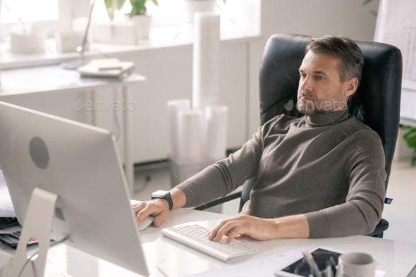 Serious manager concentrating on work while sitting in front of computer screen