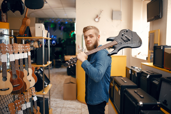 Man poses with electric guitar in music store