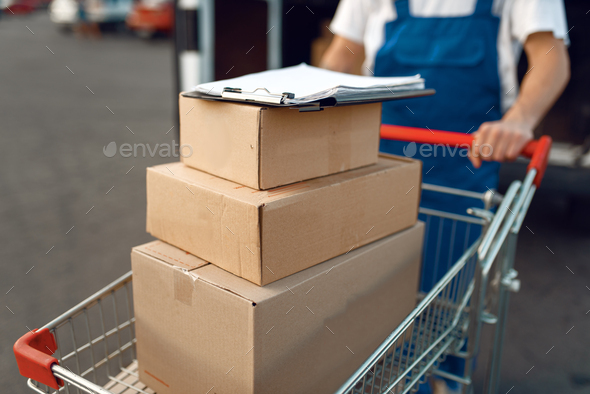 Deliveryman holds cart with stack of boxes - Stock Photo - Images