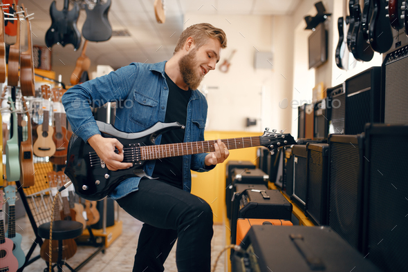 Guitarist plays on electric guitar in music store