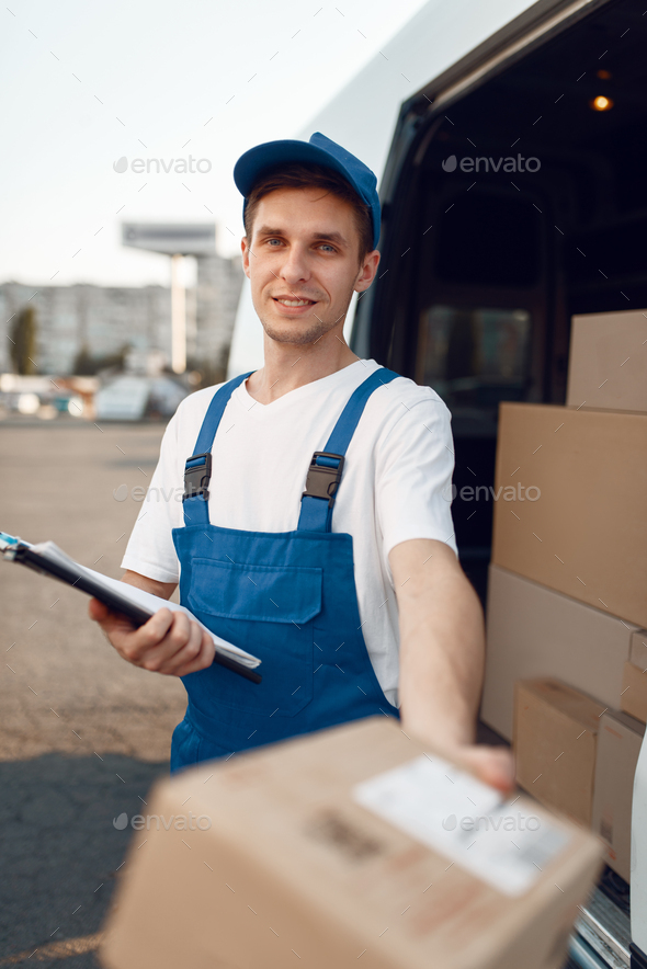 Deliveryman in uniform gives parcel, delivery - Stock Photo - Images