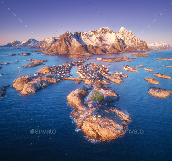 Aerial view of rocks in sea, snowy mountains, purple sky - Stock Photo - Images