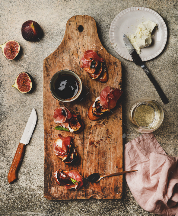 Crostini with prosciutto and glass of wineon wooden board - Stock Photo - Images