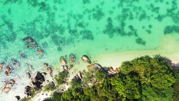 tropical sea with white sand beach, luxury bungalows and boulders. Aerial alt