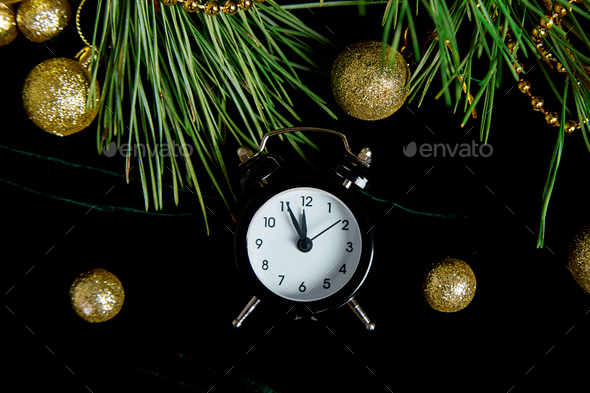 Black Alarm clock and fir tree branch, gold christmas decorations green velours - Stock Photo - Images