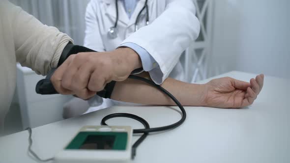 Confident Doctor Checking Blood Pressure of Patient and Giving Advices, Health