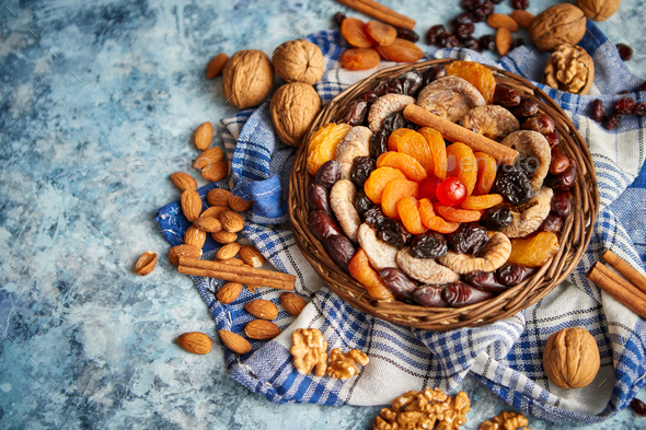 Composition of dried fruits and nuts in small wicker bowl placed on stone table - Stock Photo - Images