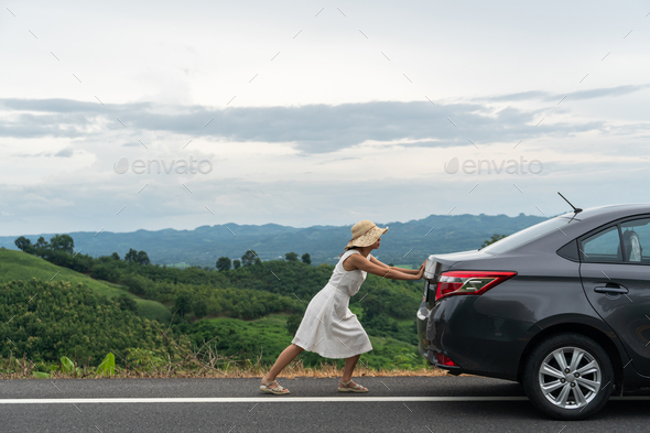 Young woman traveler pushing a broken car down the road Stock Photo by ...