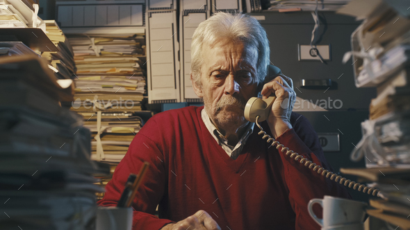 Senior businessman answering phone calls in the office - Stock Photo - Images
