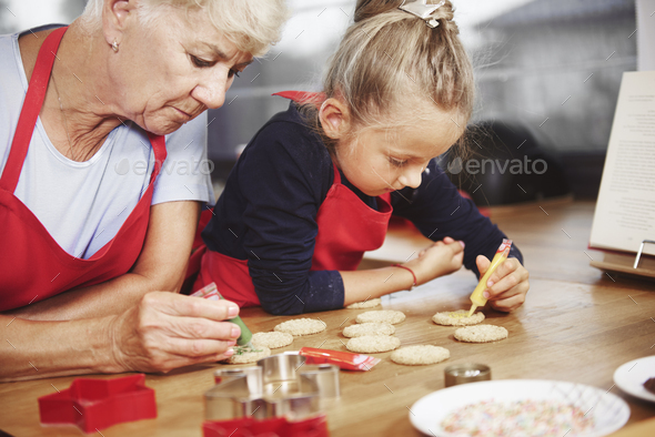 Small girl decorating cookies with her grandma