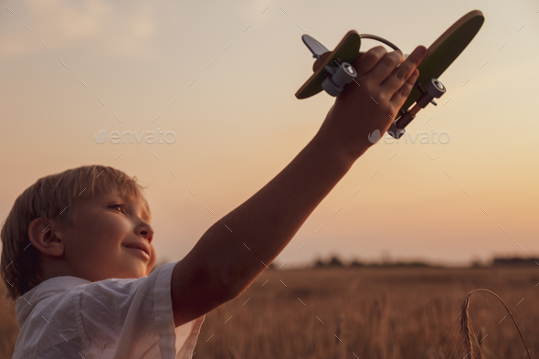 Happy child playing with a toy plane in nature during summer sun - Stock Photo - Images