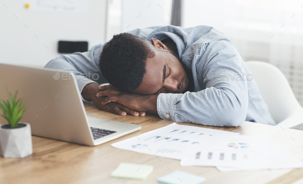 Overworked african american employee sleeping at workplace in office