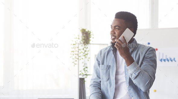 Handsome black worker talking by mobile phone in office